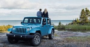 A mom and dad sitting on the back of their Jeep Wrangler JK family car | Goldstein Chrysler Jeep Dodge RAM