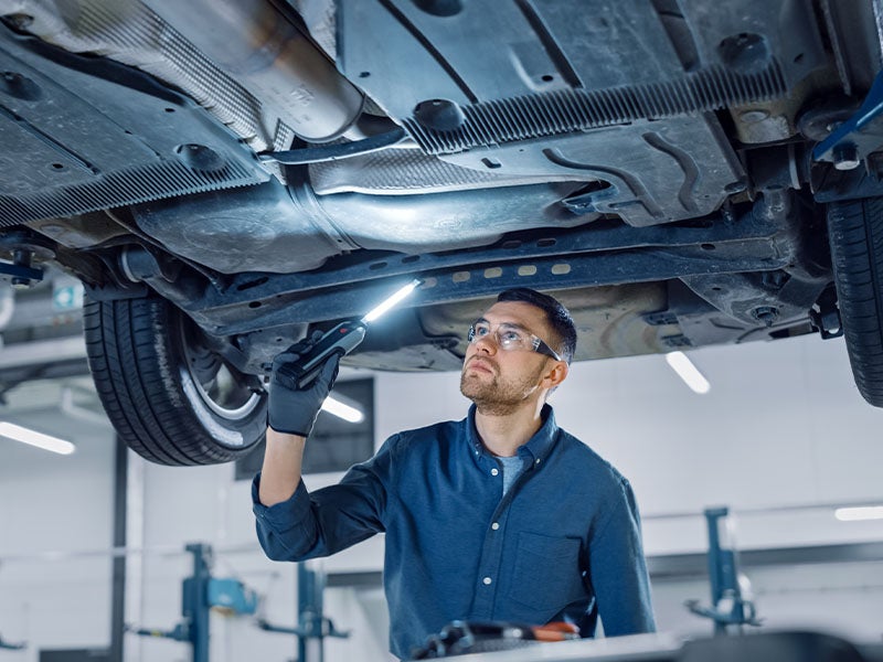 service technician inspecting underneath a vehicle
