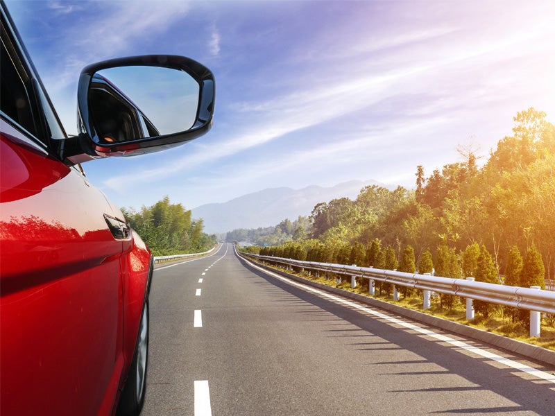 side view of a red vehicle speeding on a highway