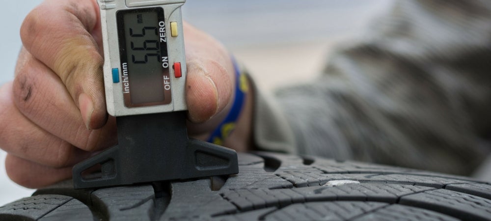 A technician checking a car's tire pressure in a blog post about oil changes and winterization