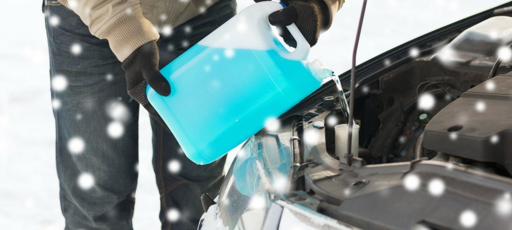 A technician adding antifreeze to a car in a blog post about oil changes and winterization
