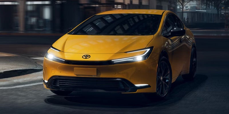 Yellow Toyota Prius driving at night.