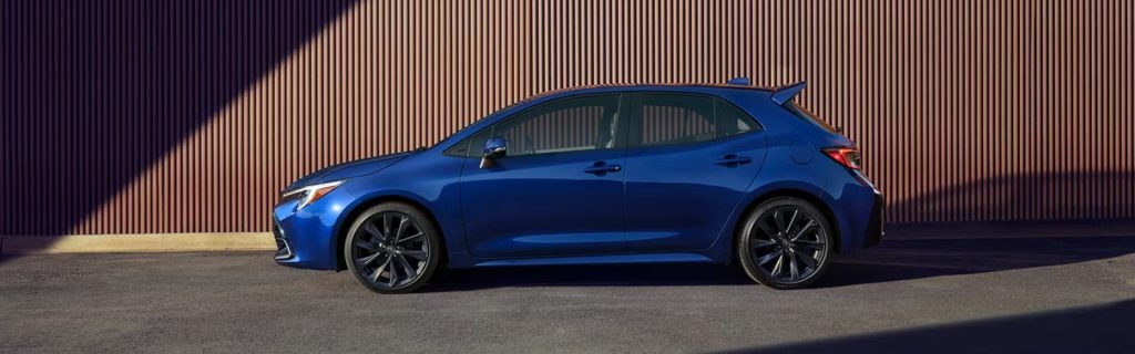 Blue Toyota Corolla Hatchback parked against a ribbed wall.