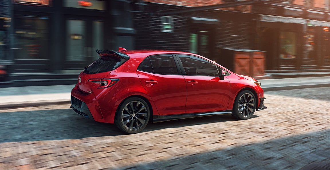 Bennett Toyota of Allentown is a Car Dealership near Westwood Heights PA in Allentown | Red 2021 Toyota Corolla Hatchback Driving Through the City