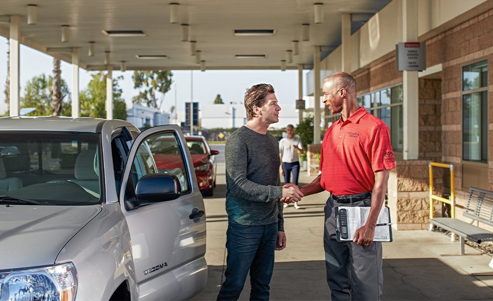 Bennett Toyota of Allentown is a Car Dealership near Allentown PA | Customer and Toyota Finance Advisor Shaking Hands While Standing Next to Silver Toyota Tacoma