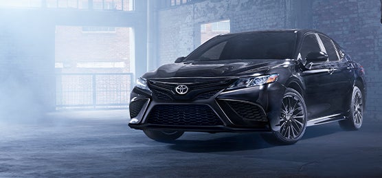 Model Features of the 2022 Toyota Camry at Bennett Toyota | Front of Camry parked in dark warehouse