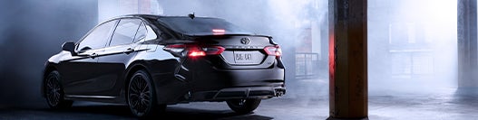 Model Features of the 2022 Toyota Camry at Bennett Toyota | Back of Camry parked in dark warehouse