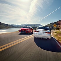 Model Features of the 2022 Toyota Camry at Bennett Toyota | Camrys pass one another on road by river