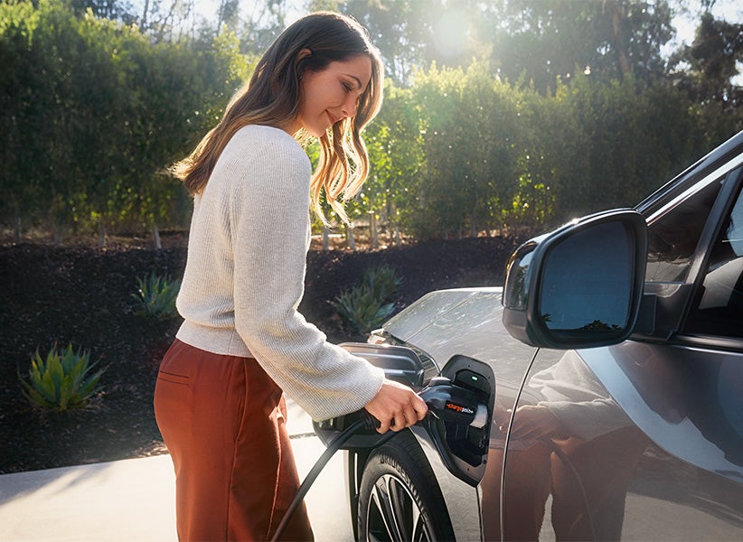The All-New Toyota Electric Car: The Toyota bZ4X BEV at Bennett Toyota of Allentown | Woman Plugging Charger Into Silver bZ4X BEV