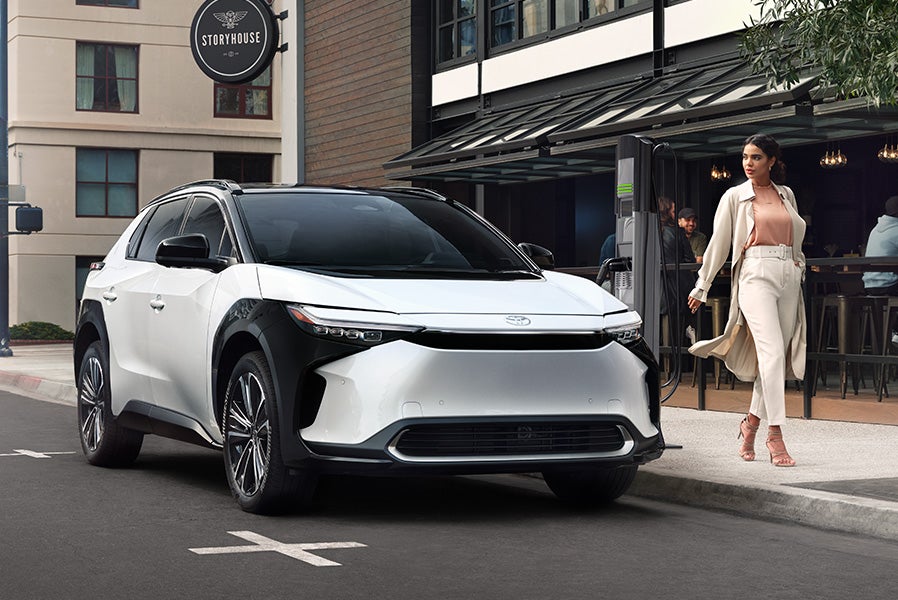 The All-New Toyota Electric Car: The Toyota bZ4X BEV at Bennett Toyota of Allentown | White bZ4X BEV Street Parked in City in Front of Restaurant