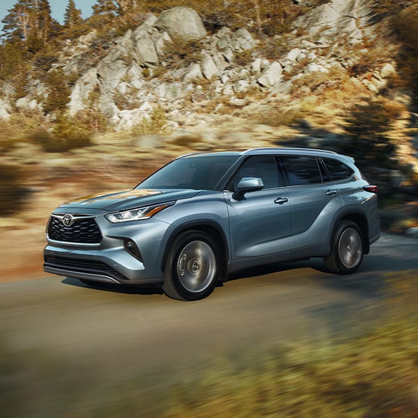 Model Features of the 2021 Toyota Highlander at Bennett Toyota | Blue 2021 Toyota Highlander Driving on Road Through Mountains
