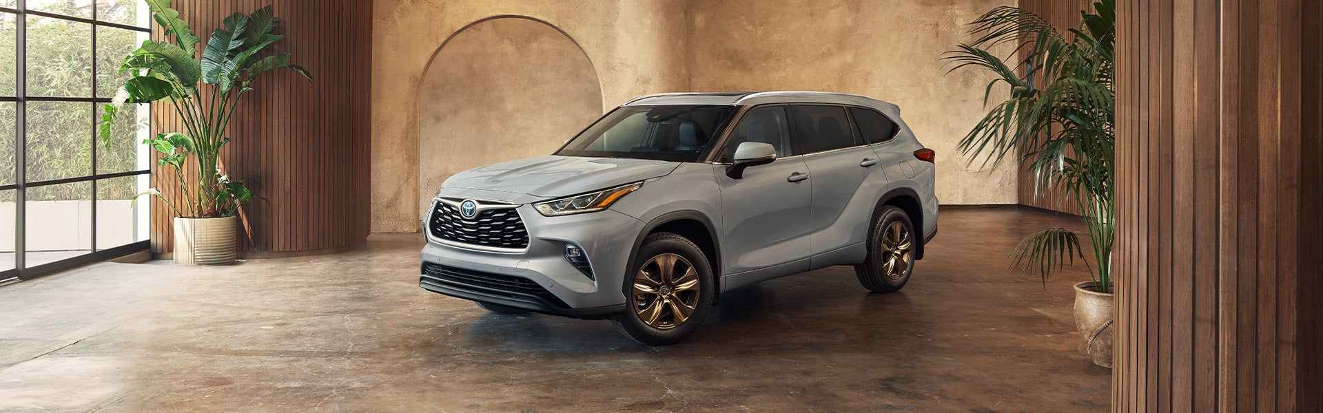 Model Features of the 2022 Toyota Highlander Hybrid at Bennett Toyota | Cool Gray Highlander Hybrid Bronze Edition Parked in Luxury Studio