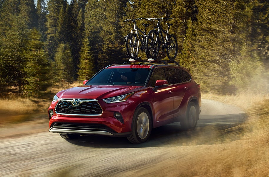 Model Features of the 2022 Toyota Highlander Hybrid at Bennett Toyota | Red Highlander Hybrid with Bike Rack Driving Fast on Dirt Road Kicking Up Dirt Behind it