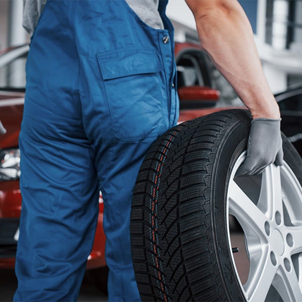 What is a Tire Rotation? at Bennett Toyota of Allentown | Service Advisor Carrying Tire Through Service Bay