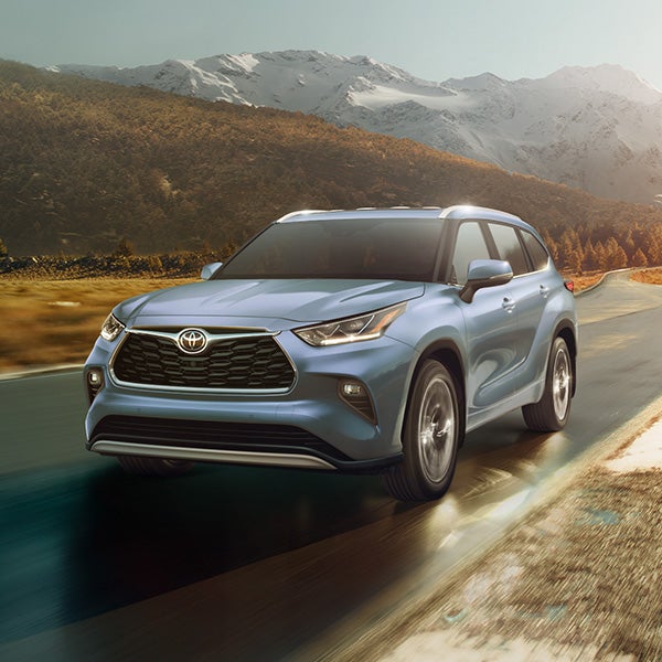The 2022 Toyota Highlander vs. The 2021 Toyota Highlander at Bennett Toyota | Light Blue 2022 Toyota Highlander Driving on Road with Mountains in the Background