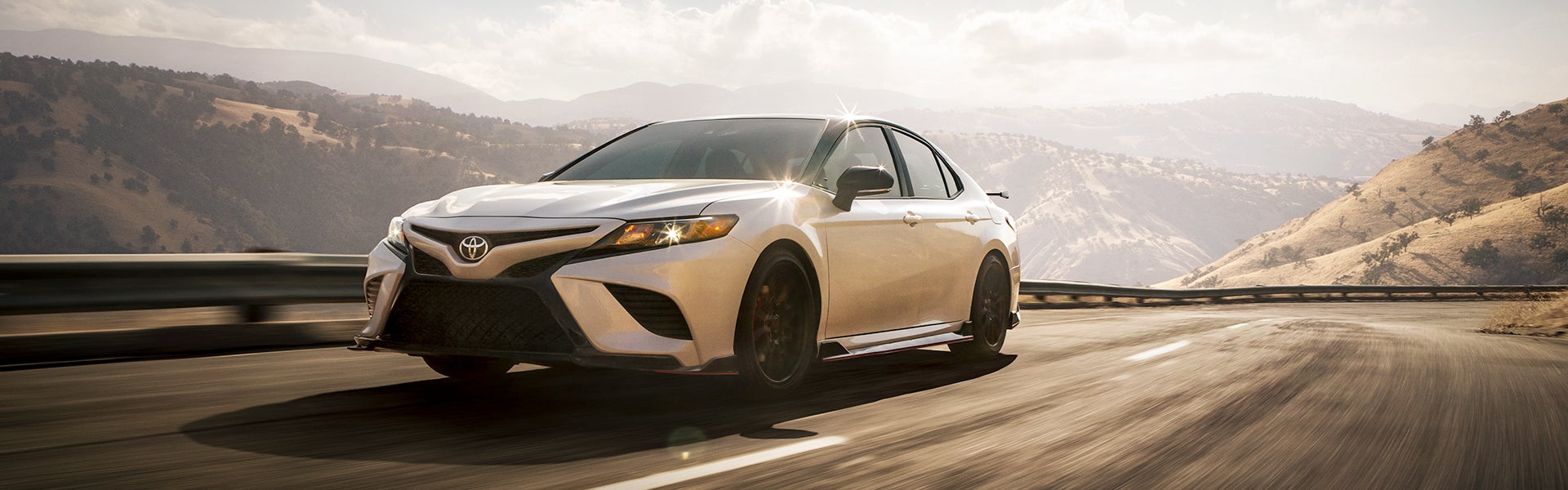 The 2021 Toyota Camry vs. The 2021 Honda Accord at Bennett Toyota | White 2021 Toyota Camry TRD Pro Driving Around on Road Overlooking Mountains