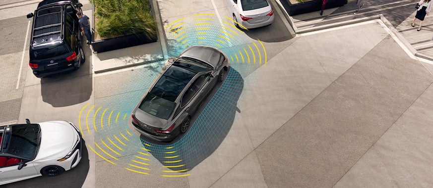 The 2021 Toyota Camry vs. The 2021 Honda Accord at Bennett Toyota | Brown 2021 Toyota Camry Using Toyota Safety Sense P Software to Keep Track of Cars Around it While Backing Out of Parking Spot