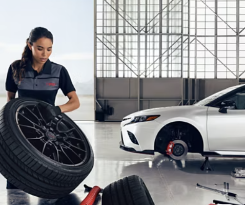 Toyota technician carrying a wheel during tire service