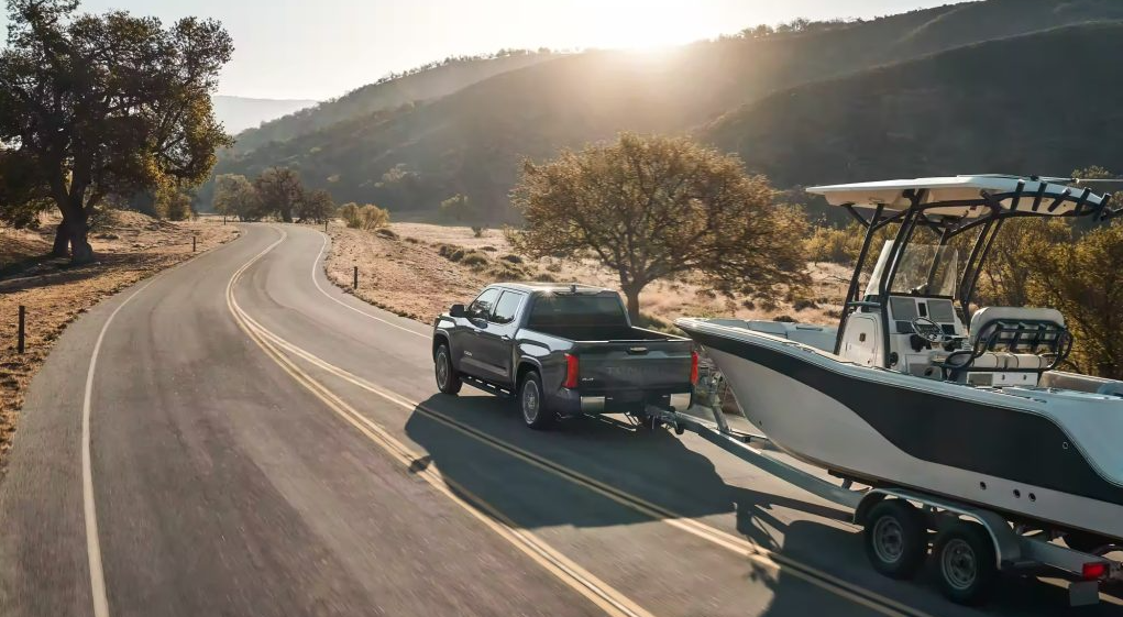 High-angle view of a pickup truck towing a boat trailer in afternoon sunlight