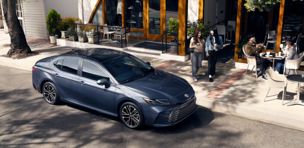 2026 Toyota Camry sedan parked outside a modern cafe on a city street