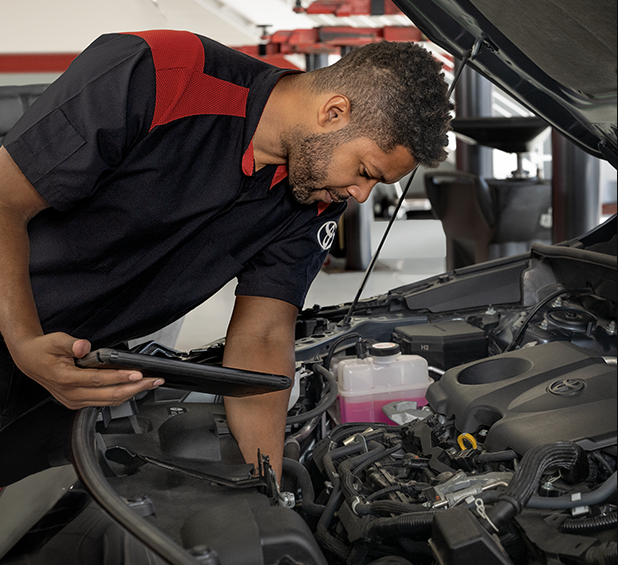 Toyota technician inspecting a vehicle engine during service