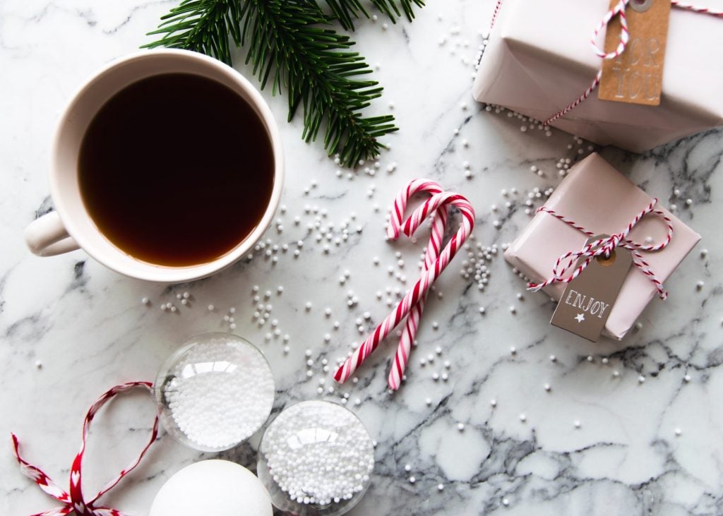 two peppermint candy canes and coffee and presents by fir branch